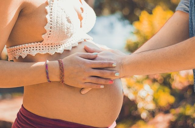 Kobieta w ciąży i mężczyzna trzymający ręce na brzuchu